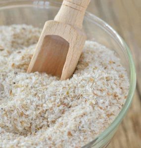 Weiße Flohsamenschalen im Glas mit Holzschäufelchen