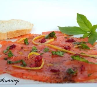 Lachscarpaccio mit Granatapfelkernen, Zesten einer Zitrusfrucht und Basilikum