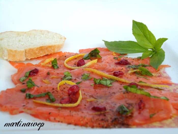 Lachscarpaccio mit Granatapfelkernen, Zesten einer Zitrusfrucht und Basilikum