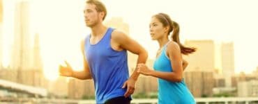 Junger Mann und junge Frau mit blauen T-Shirts joggen nebeneinander mit optimalem Trainingspuls