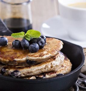 Pancakes in einer schwarzen Pfanne mit Blaubeeren garniert