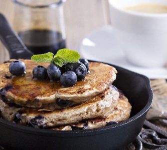 Pancakes in einer schwarzen Pfanne mit Blaubeeren garniert