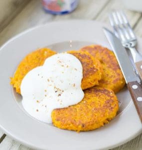 Drei Möhren-Couscous-Bratlinge mit Quark auf weißem Teller serviert