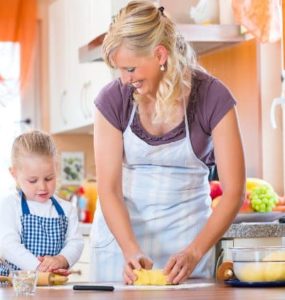 Mutter und Kind mit Schürze backen Plätzchen