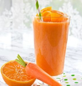 1 Glas A-C-E-Smoothie mit Strohhalm. Davor eine halbe Orange und eine Karotte