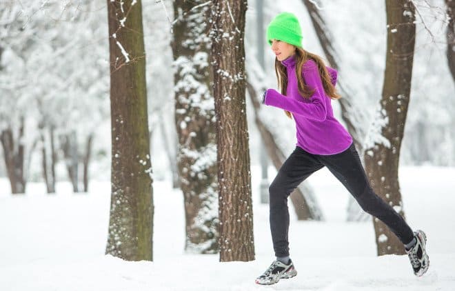 Frau im wintertauglichen Fitness-Outfit joggt durch den Wald