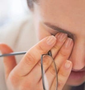 Im Büro arbeitende Frau, die sich vor Müdigkeit die Augen reibt