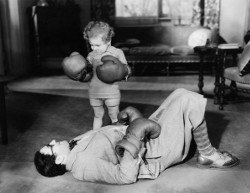 Kind schlägt Mann ko mit Boxhandschuhen.