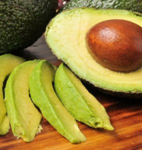 Avocados als ganze Frucht, halbiert und in Streifen geschnitten