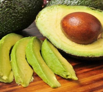 Avocados als ganze Frucht, halbiert und in Streifen geschnitten