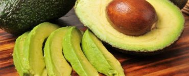 Avocados als ganze Frucht, halbiert und in Streifen geschnitten