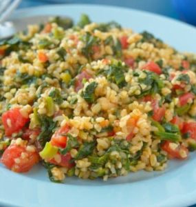 Bulgur mit Spinat und Tomate auf einem hellblauen Teller