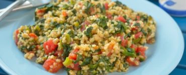 Bulgur mit Spinat und Tomate auf einem hellblauen Teller