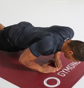 Mann macht Diamond Push Ups auf dunkelroter Trainingsmatte