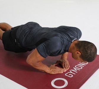 Mann macht Diamond Push Ups auf dunkelroter Trainingsmatte