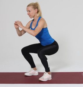 Frau macht Squat auf roter Trainingsmatte