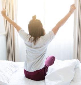 Morgen Routine - Frau räkelt sich im Bett nach dem Aufstehen