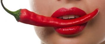 Frau mit Chilischote im Mund mit Lippenstift