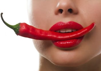 Frau mit Chilischote im Mund mit Lippenstift