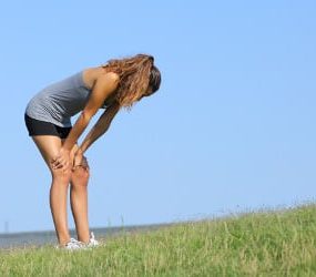 Eine Sportlerin mit Heuschnupfen steht erschöpft auf einer Wiese.