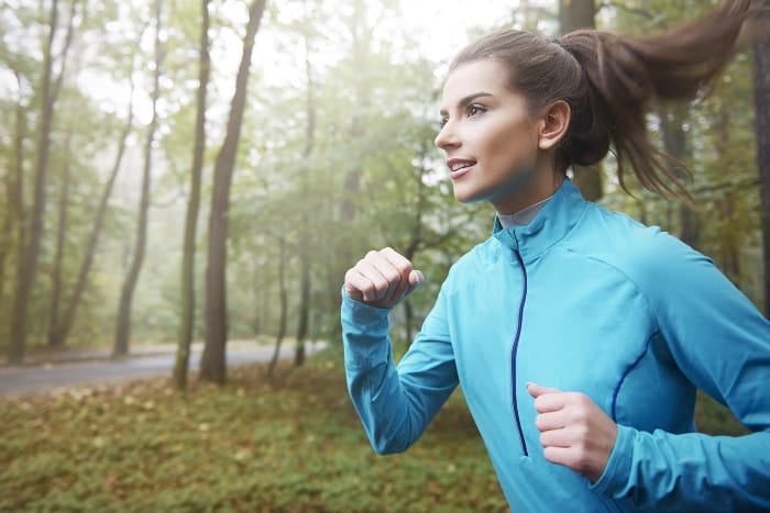 frau mit pferdeschwanz frisur joggt durch den wald