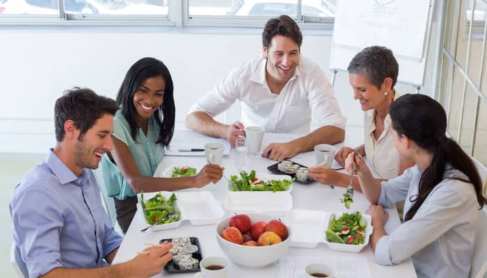 Fünf Büroarbeiter essen gemeinsam gesundes Essen zum Mittag