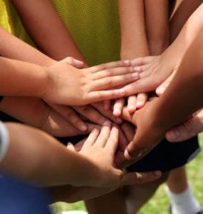 Hände die auf einem Huddle zusammen gelegt sind.