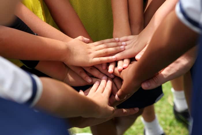 Hände die auf einem Huddle zusammen gelegt sind.