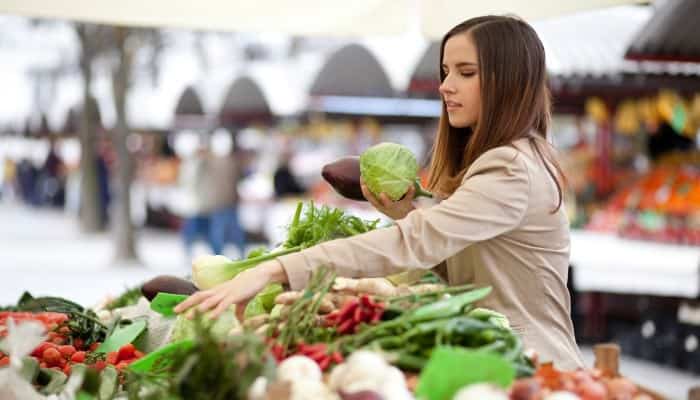 Frau kauft Gemüse auf dem Markt