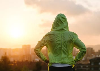 Frau im Sportdress blickt gen Sonnenuntergang