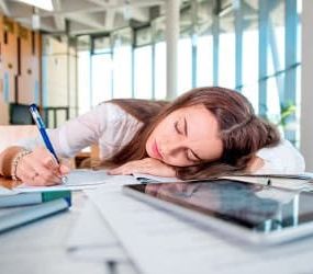 Frau schläft auf Schreibtisch