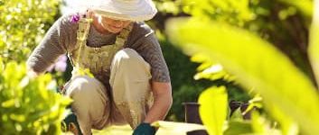 Frau arbeitet kniend im Garten