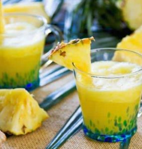 Ananas-Smoothie mit Ingwer in einem Glas, das mit 1/8 Ananasscheibe dekoriert wurde.