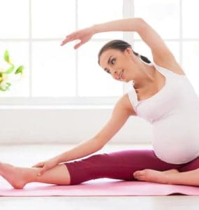 schwangere frau macht yoga seitbeuge