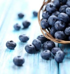 heidelbeeren in korb auf hellblauem tisch