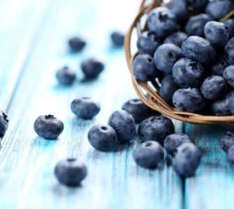 heidelbeeren in korb auf hellblauem tisch