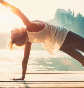 Junge Frau macht Yoga am See und fühlt sich wohl