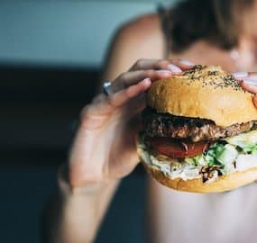 Frau hat Hunger und hält Burger in den Händen