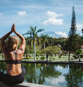 Junge Frau sitzt im Lotussitz und macht Yoga auf bali