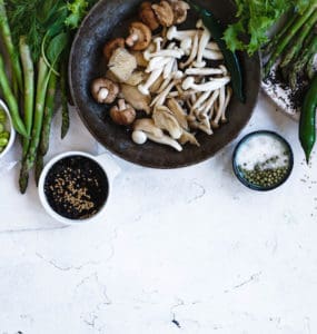 Tisch gedeckt mit Tellern voller gesunder, vegetarischer und veganer Lebensmitteln. Pilze, Sojabohnen, Gemüse