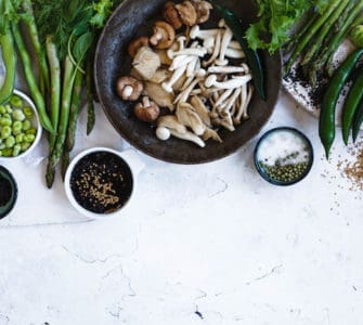 Tisch gedeckt mit Tellern voller gesunder, vegetarischer und veganer Lebensmitteln. Pilze, Sojabohnen, Gemüse