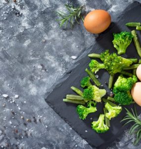 broccoli und eier auf brett dunkelgrauer tisch