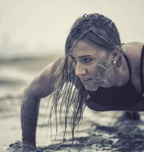 Trainierte Frau macht Crawling Fitness und krabbelt durch den Schlamm