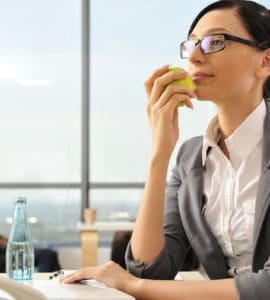 Frau isst gesund am Arbeitsplatz