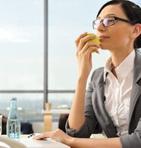 Frau isst gesund am Arbeitsplatz