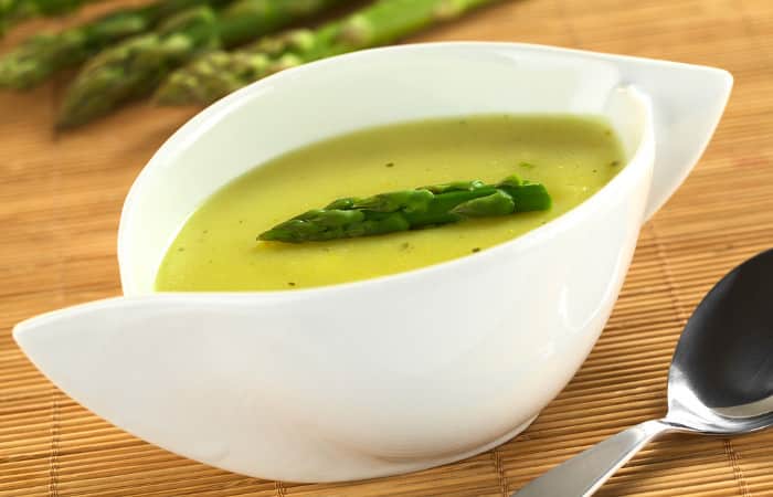 Spargelsuppe in weißer Keramikschüssel mit grüner Spargel in ihrer Mitte