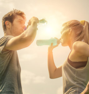 Frau und Mann stehen sich gegenüber und trinken Wasser