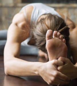 Junge Frau auf Yogamatte macht eine Vorbeuge